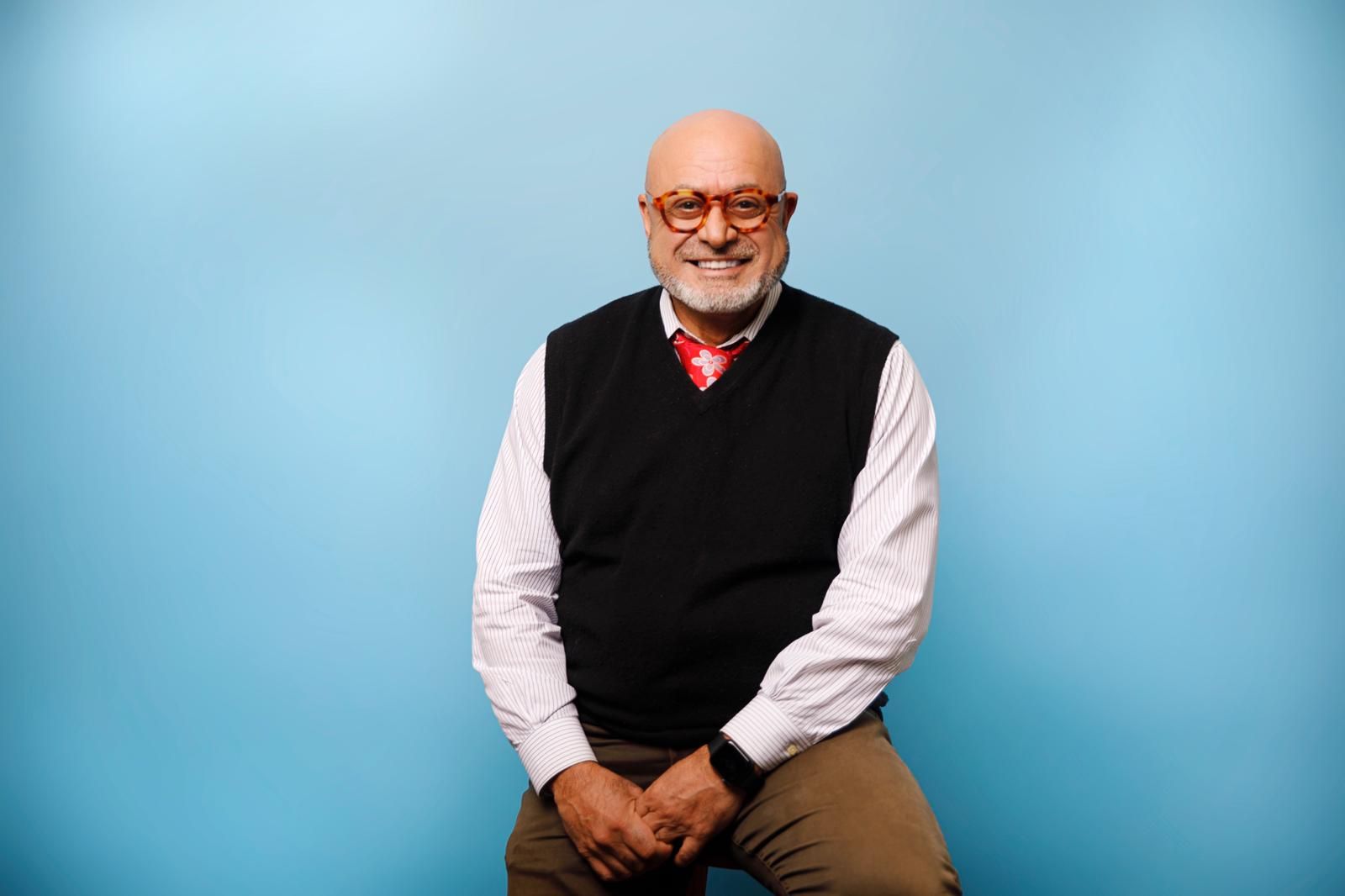 Portrait of Sassan Zabeti, founder of Zabeti Life Academy, smiling and seated against a blue background.